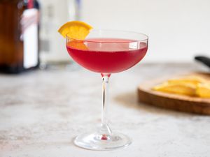 Side view of a Autumn-spiced cosmopolitan garnished with an orange wedge.