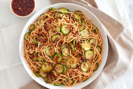 Large bowl of spicy noodles with cucumbers and chili crisp.