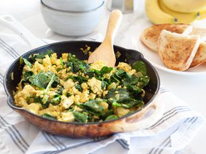 Vegan spinach and tofu scramble in skillet with toast on side.