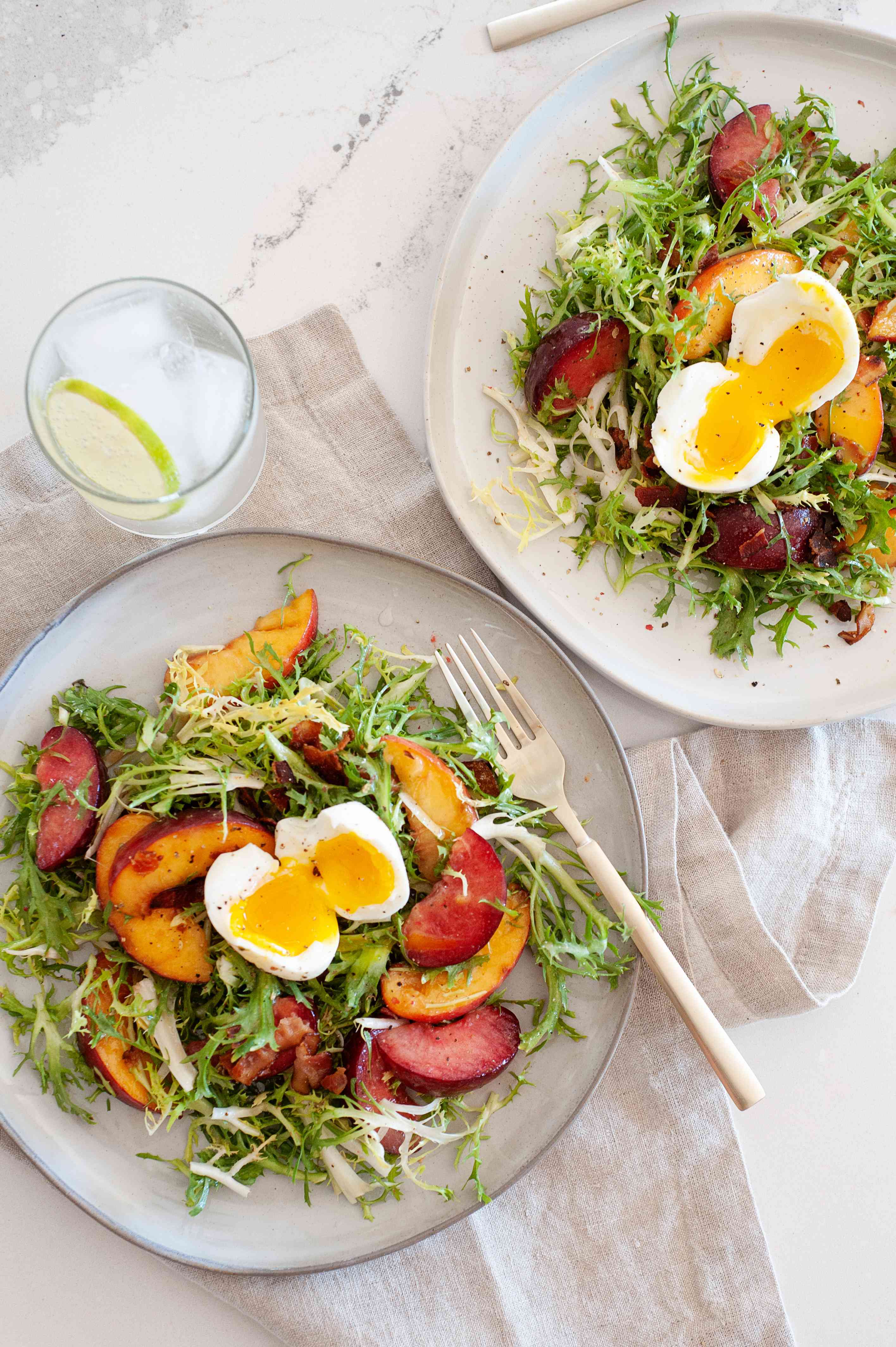 Overhead view of summer fruit frisée salad topped with a hard boiled egg.