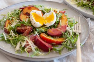 Side view of a summer-y salad with stone fruit and frisée.