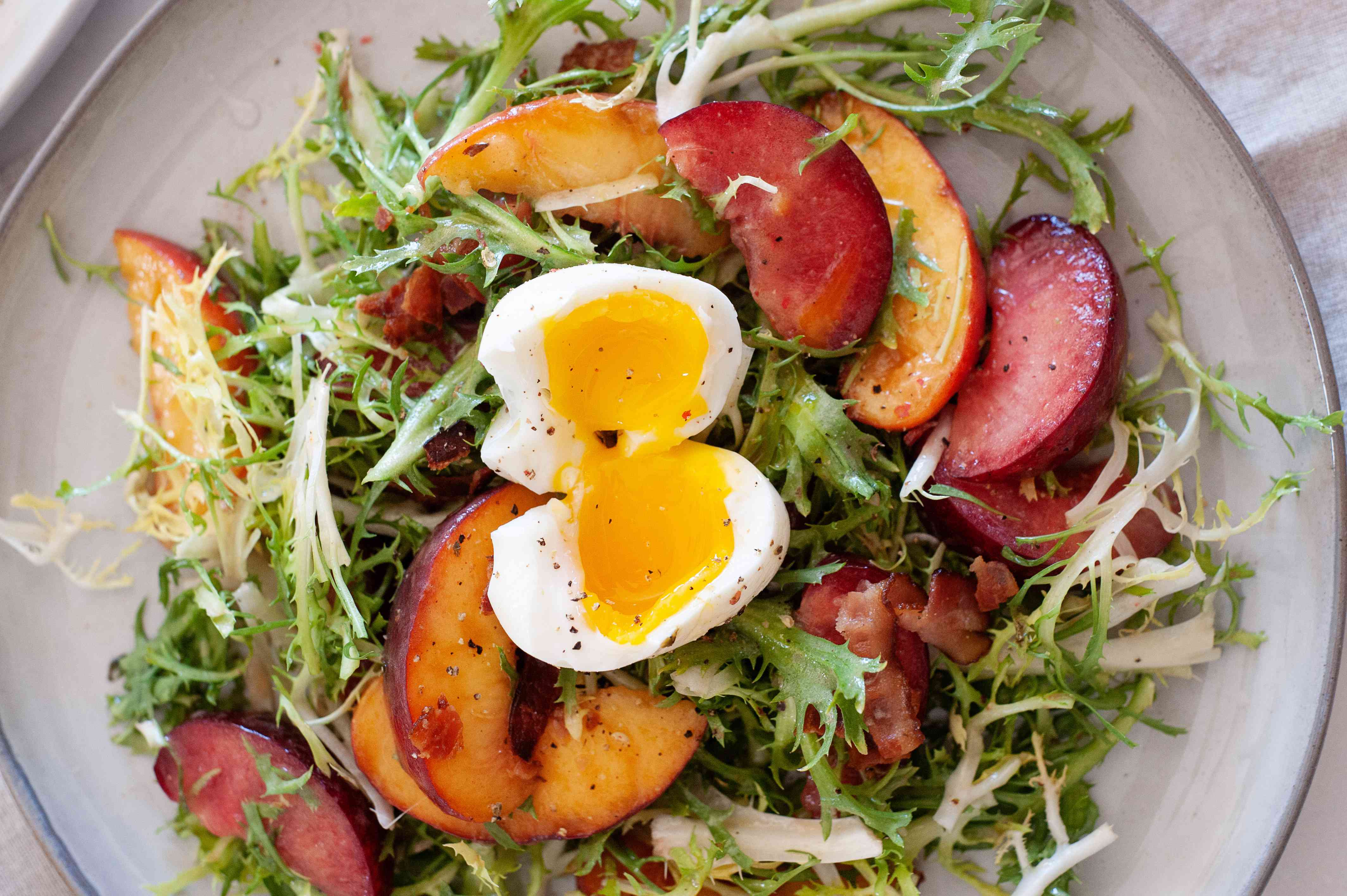 Overhead view of a summer-y salad with stone fruit and frisée.
