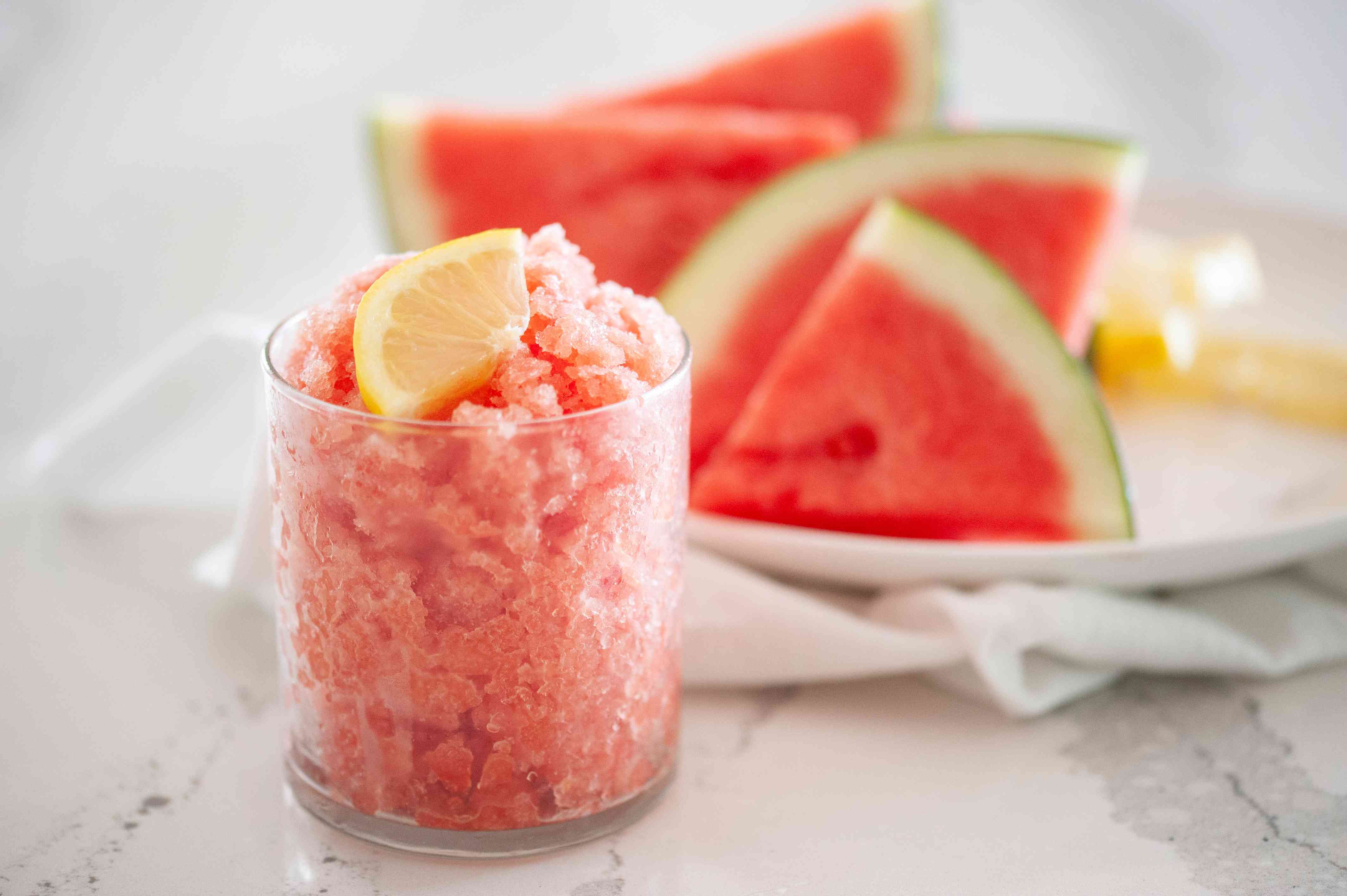 Side view of a watermelon granita with watermelon behind it.