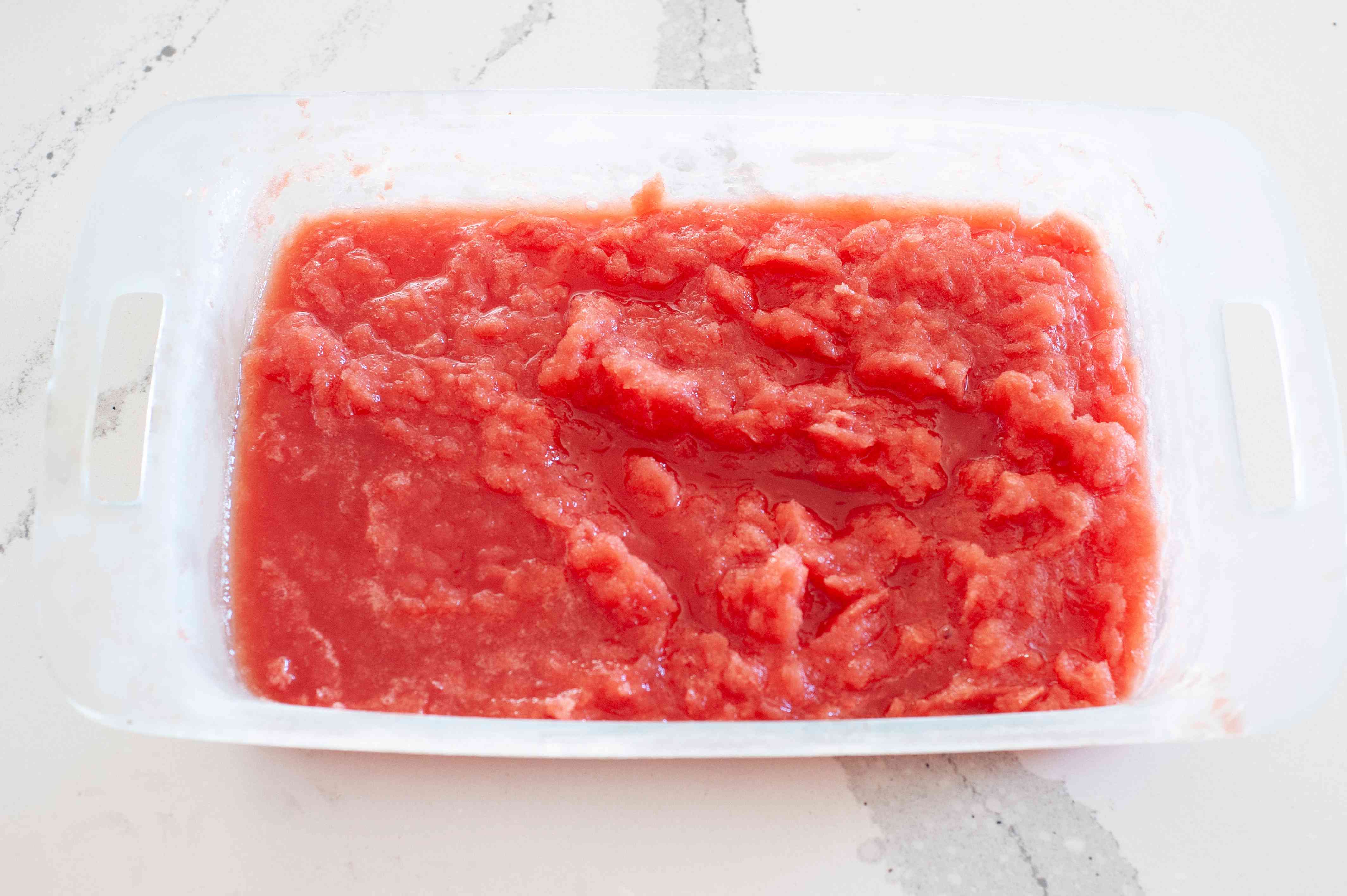How to make a watermelon granita recipe showing partially frozen watermelon mixture in a glass baking pan.