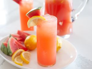 Whole lemon and watermelon lemonade in tall glasses and garnished with lemon and watermelon.