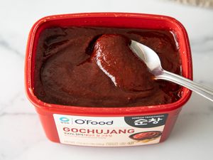 A scoop of gochujang in classic red tub
