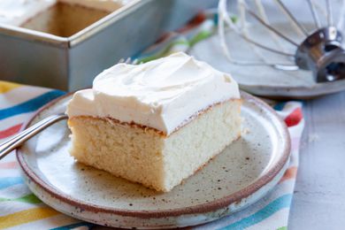 Easy white cake topped with frosting and on a plate.