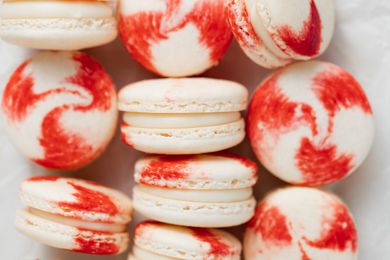 Overhead view of peppermint macarons with white chocolate filling on a baking sheet.