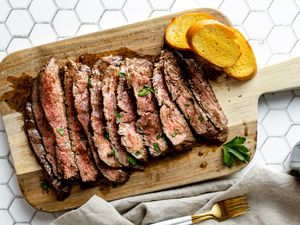 Overhead view of a flank steak sliced on a cutting board.